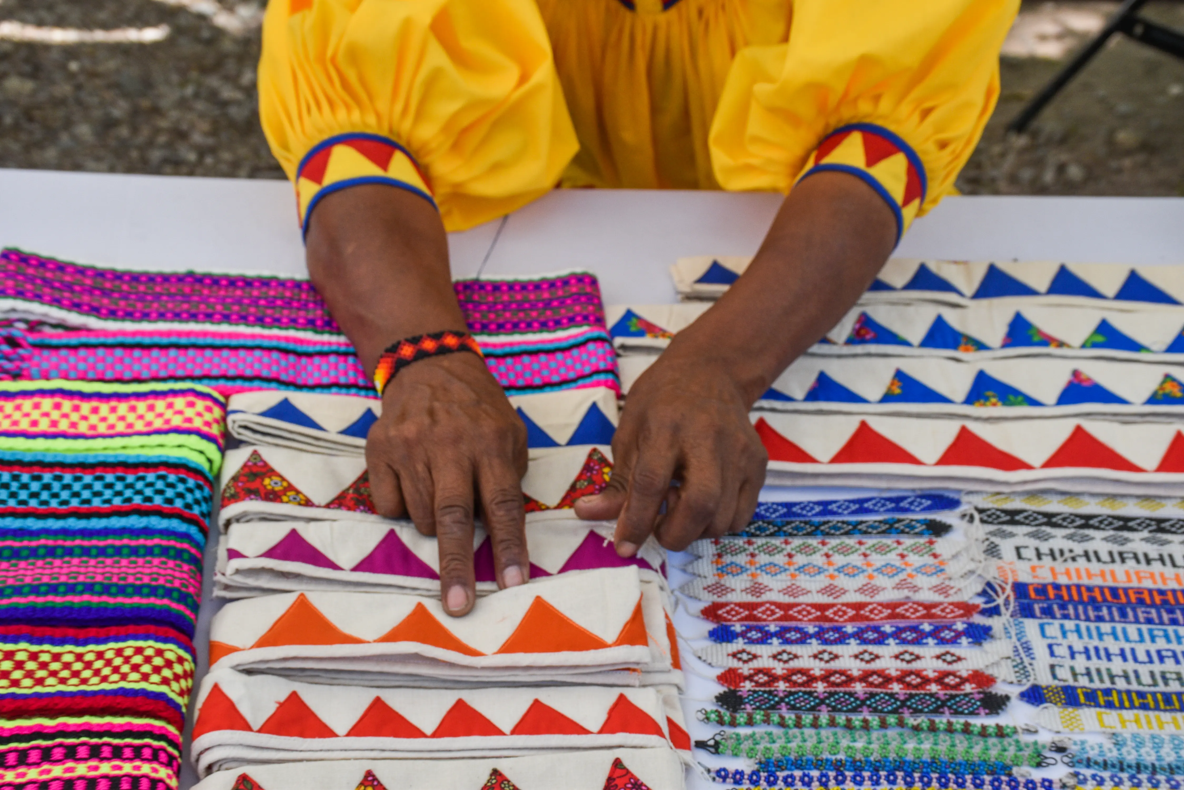 Manos artesanas ordenando textiles bordados en Chihuahua, México.